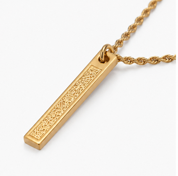 Macro close up shot of intricate traditional Arabic calligraphy engraving on a sleek gold rectangular bar necklace.