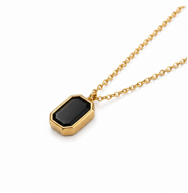 Angled close up view of Zafiroon tarnish free gold necklace featuring an emerald cut black stone card pendant.