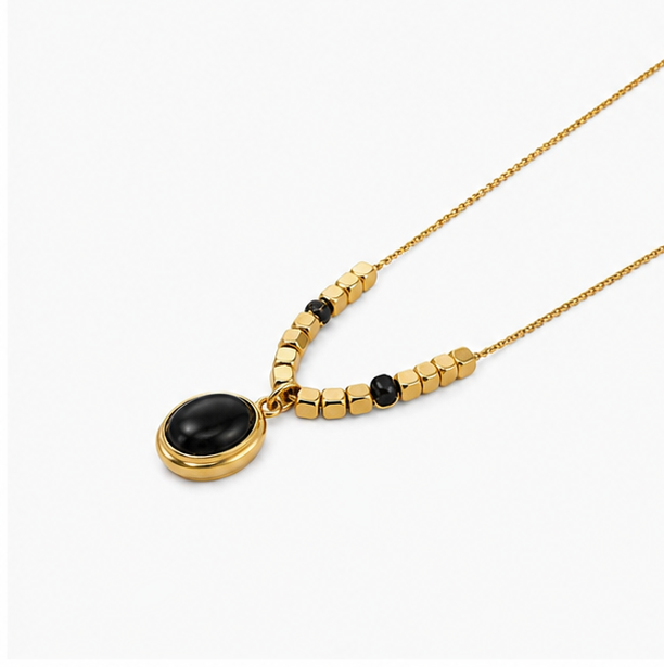 Vintage gold plated stainless steel oval black onyx cabochon pendant necklace with a row of geometric gold cube beads on a plain white background
