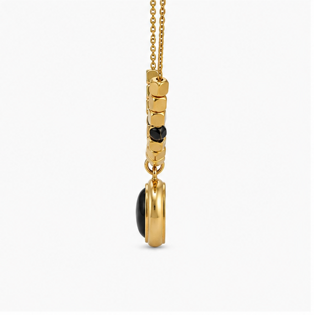 Vertical side profile view of Zafiroon oval black pendant suspended to demonstrate the thickness of the golden bezel and cube beads.