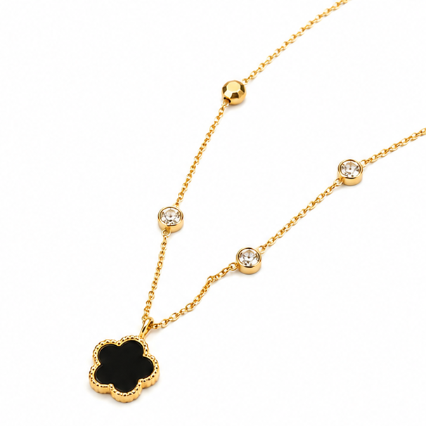 High angle shot of a luxury gold tone dainty floral medallion necklace with sparkling crystal droplets on white backdrop.