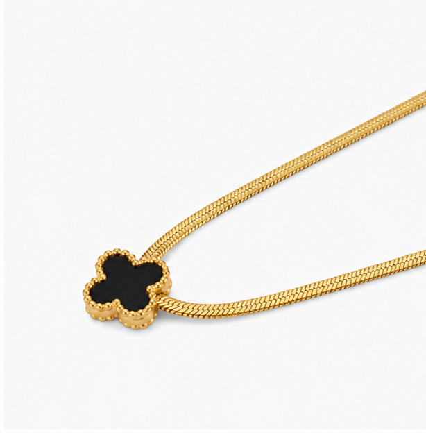 Angled macro shot of Zafiroon gold clover pendant showcasing the beaded gold border and flat metallic snake chain structure.