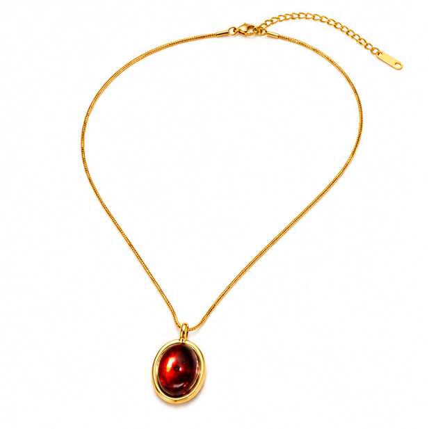 Full layout flat lay of a gold plated oval red stone necklace showing the adjustable lobster clasp and extender chain.